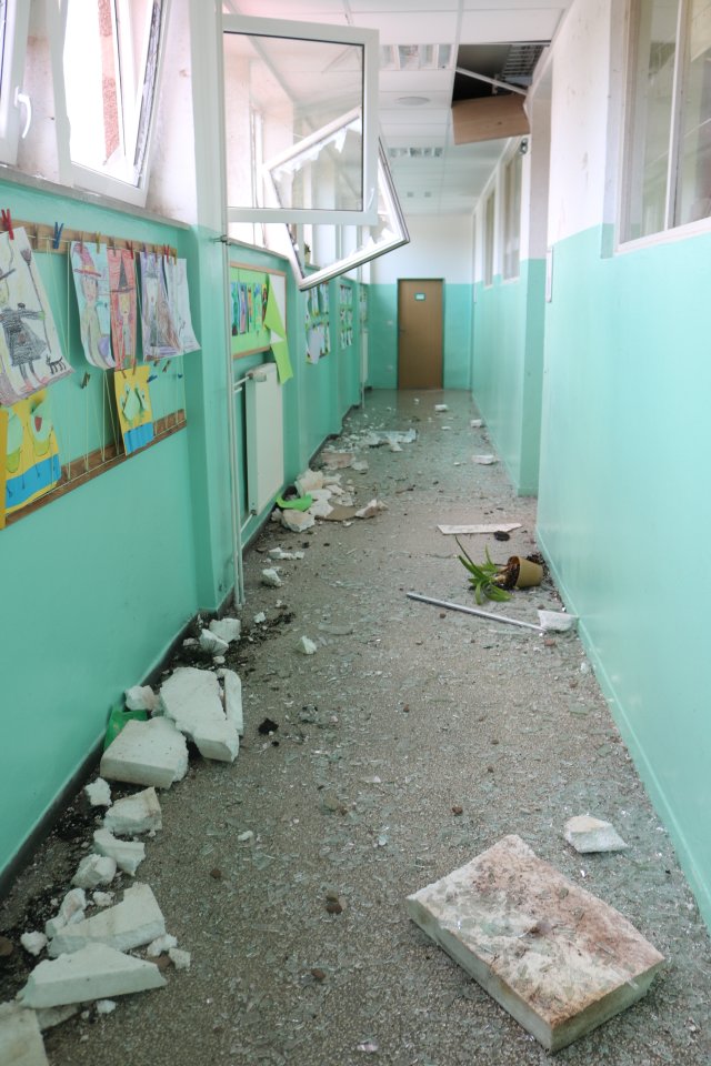 Zniszczony korytarz szkolny. wyrwane okna porozrzucane fragmenty elewacji.