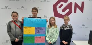 cztery dziewczynki stoją z kolorowym plakatem