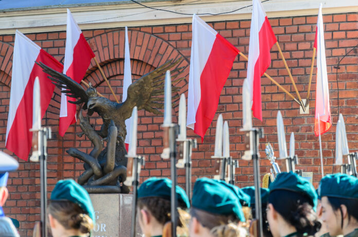 flagi polskie na tle pomnika Żołnierzy Wyklętych