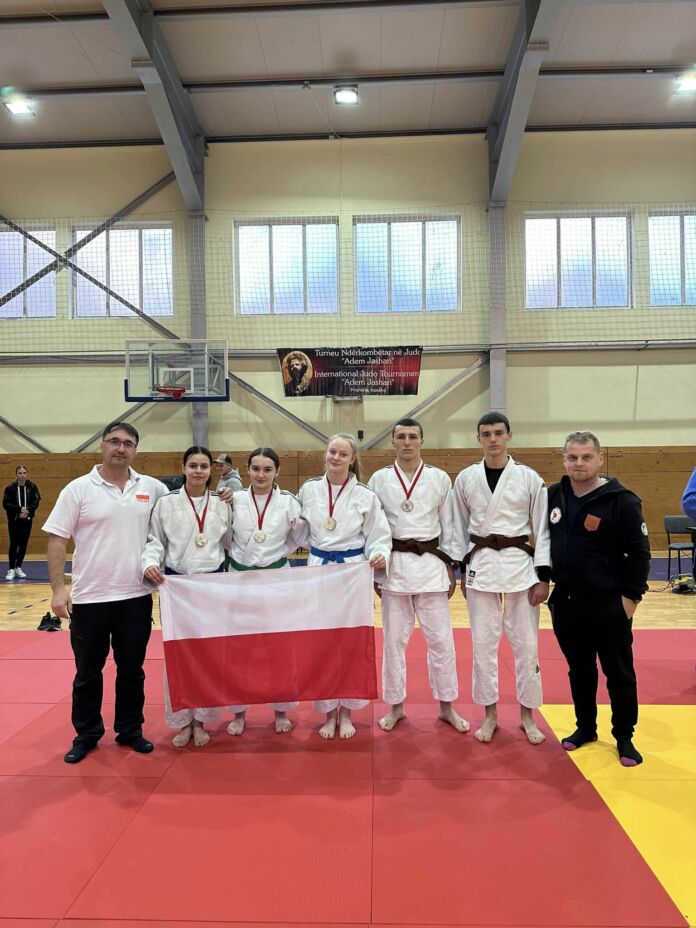 Zdjęcie zawodników i trenerów UKS ASW Judo Jasło z flagą podczas trwania Turnieju